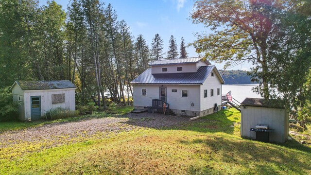 back of house with a shed and a lawn