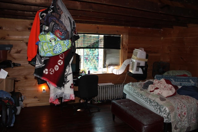 bedroom with radiator heating unit, wood-type flooring, and beam ceiling