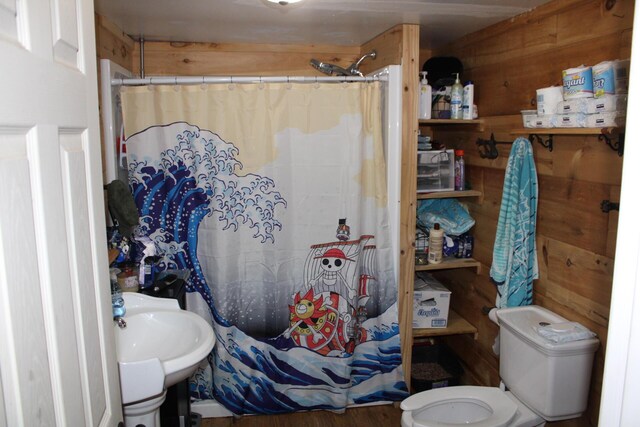 bathroom featuring wooden walls, curtained shower, and toilet