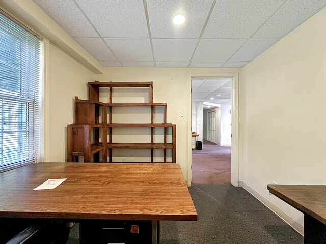 unfurnished office with dark carpet and a paneled ceiling