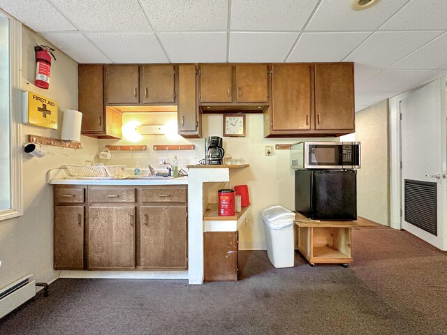 kitchen with dark colored carpet, baseboard heating, and a paneled ceiling