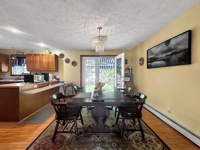 dining space with hardwood / wood-style flooring, a baseboard radiator, a notable chandelier, and a textured ceiling