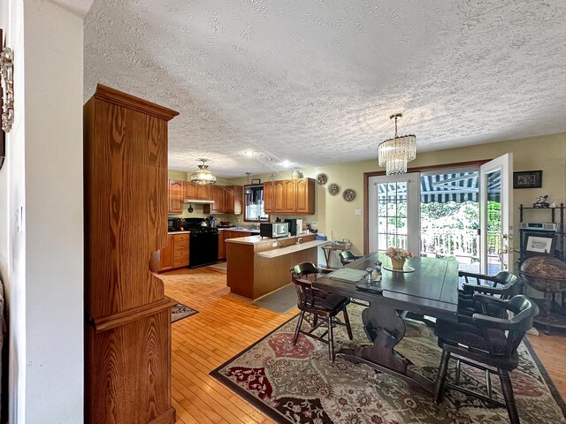 dining space with a textured ceiling, light hardwood / wood-style floors, and a chandelier