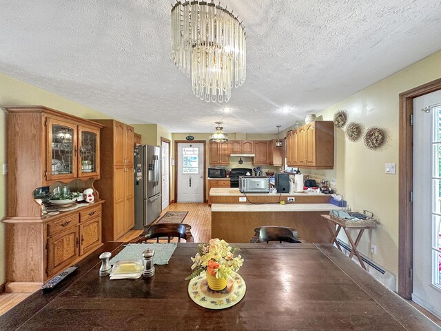 dining area with an inviting chandelier, light wood-type flooring, and a textured ceiling