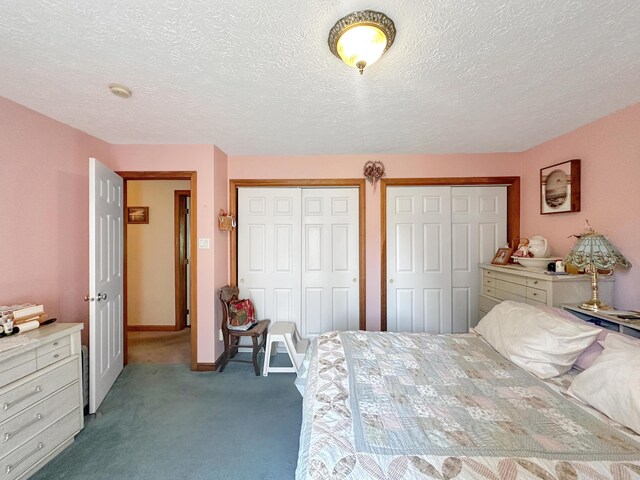 carpeted bedroom with a textured ceiling and two closets