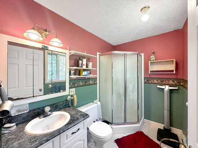 bathroom featuring tile patterned flooring, a textured ceiling, walk in shower, vanity, and toilet