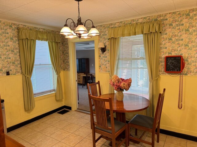 tiled dining area featuring crown molding, an inviting chandelier, and a healthy amount of sunlight