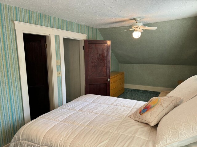 bedroom with vaulted ceiling, a textured ceiling, and ceiling fan