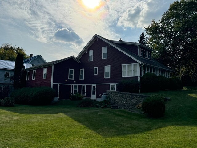 back house at dusk featuring a lawn