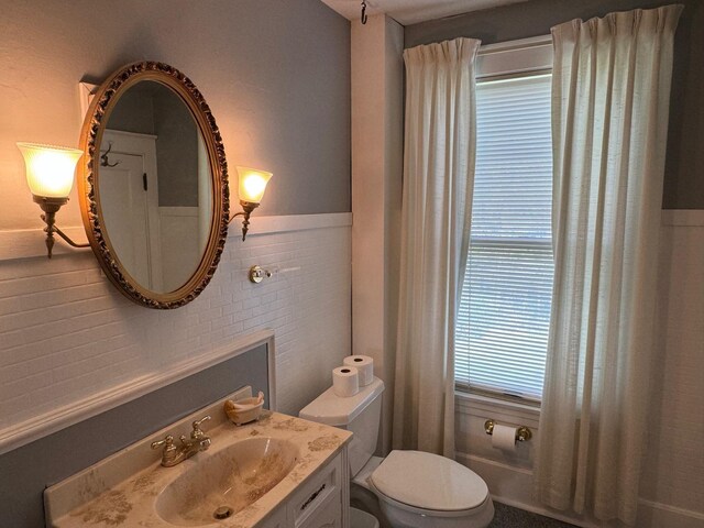 bathroom with vanity, tile walls, and toilet