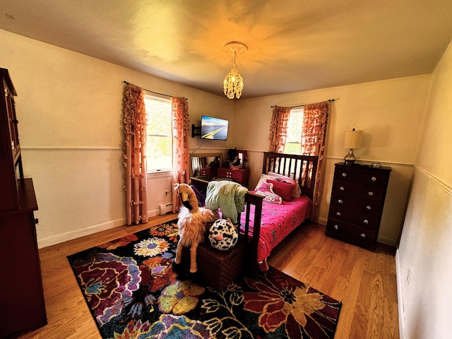 bedroom featuring multiple windows, light wood-type flooring, and a baseboard radiator