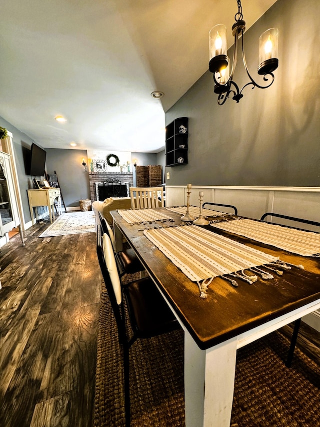 dining area featuring a notable chandelier, a brick fireplace, and hardwood / wood-style floors