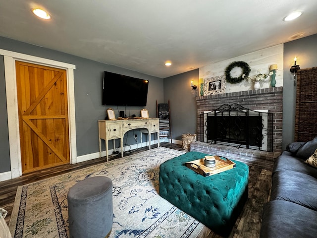 living room with a brick fireplace and wood-type flooring