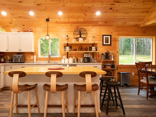 kitchen featuring lofted ceiling, white cabinets, wooden ceiling, a breakfast bar area, and decorative light fixtures