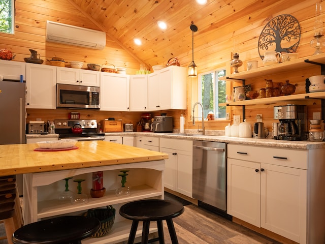 kitchen featuring stainless steel appliances, pendant lighting, white cabinets, and lofted ceiling