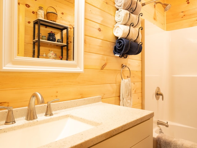 bathroom featuring vanity, wooden walls, and  shower combination