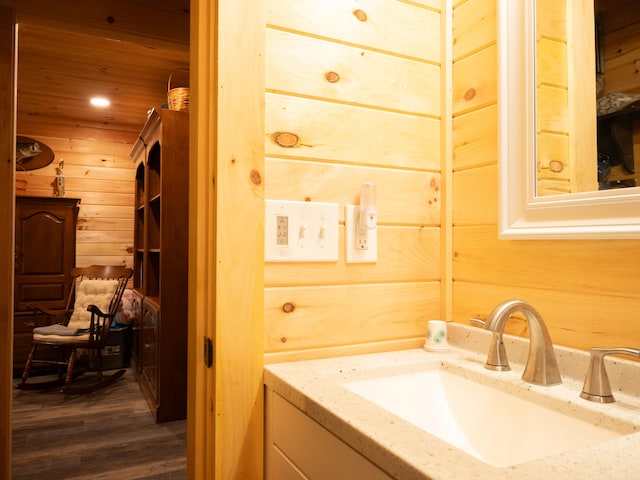 bathroom with wood walls, vanity, and wood-type flooring