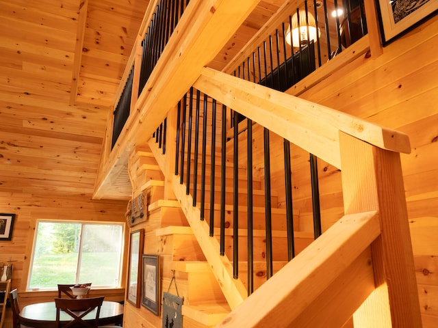 stairway with wooden walls, a towering ceiling, and wooden ceiling