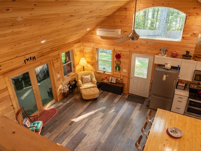 interior space with ceiling fan, wood ceiling, dark hardwood / wood-style floors, vaulted ceiling, and wood walls