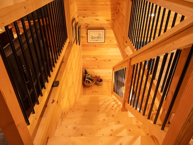 staircase with wood walls and wood-type flooring