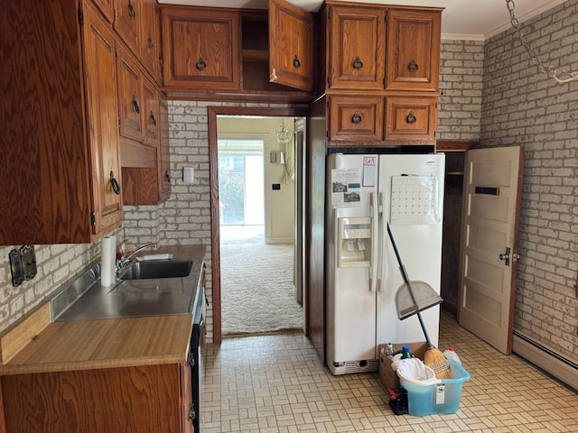 kitchen with crown molding, baseboard heating, light carpet, white fridge with ice dispenser, and sink