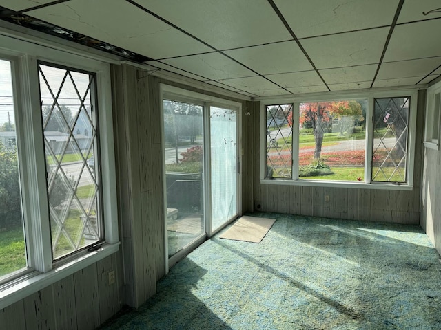 unfurnished sunroom featuring a drop ceiling and a healthy amount of sunlight