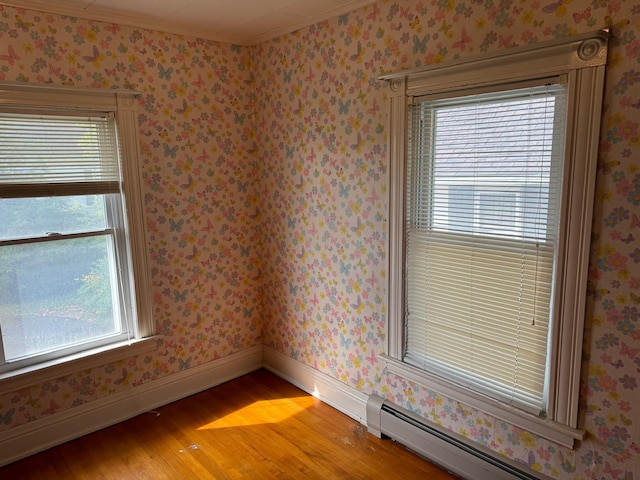 empty room featuring a baseboard radiator, hardwood / wood-style floors, and a wealth of natural light