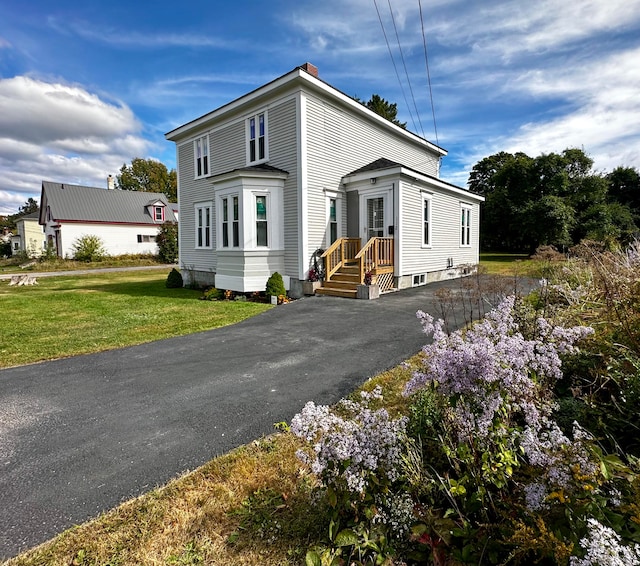 view of front of house featuring a front yard, driveway, and a chimney