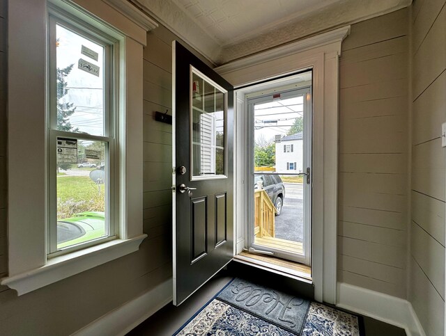 entryway featuring baseboards and wooden walls