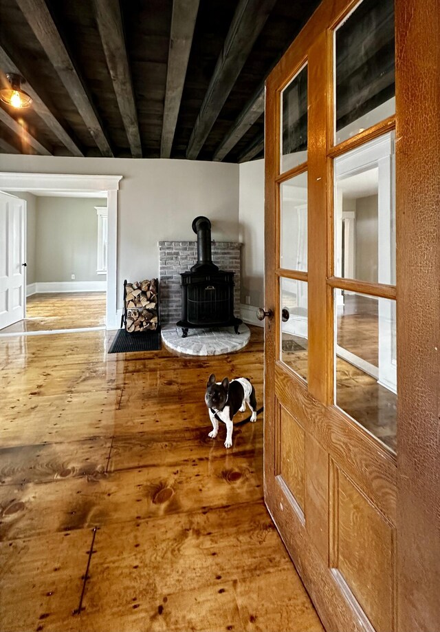 interior details featuring beamed ceiling, wood finished floors, and a wood stove