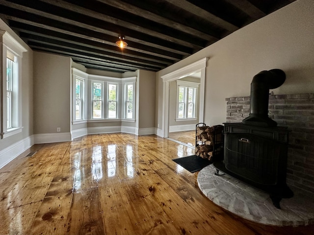 112 S St, Calais, ME 04619 - living room with a wood stove, hardwood / wood-style floors, beam ceiling, and baseboards
