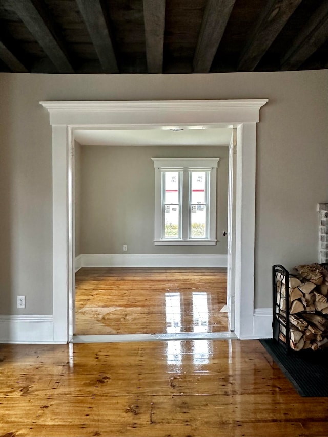 empty room with beamed ceiling and hardwood / wood-style flooring