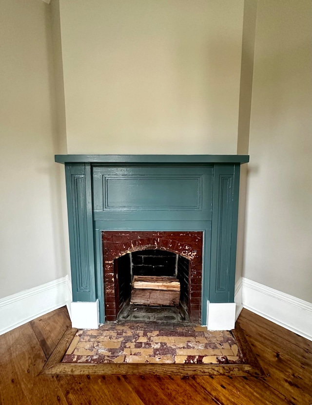 details featuring a fireplace with flush hearth, wood finished floors, and baseboards