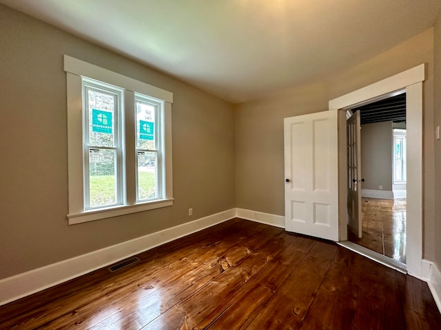 spare room with visible vents, baseboards, and dark wood finished floors