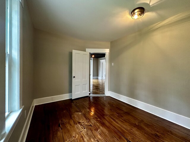 unfurnished room featuring dark wood-style floors and baseboards