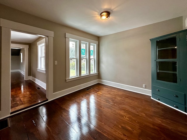 unfurnished room featuring visible vents, baseboards, and wood-type flooring