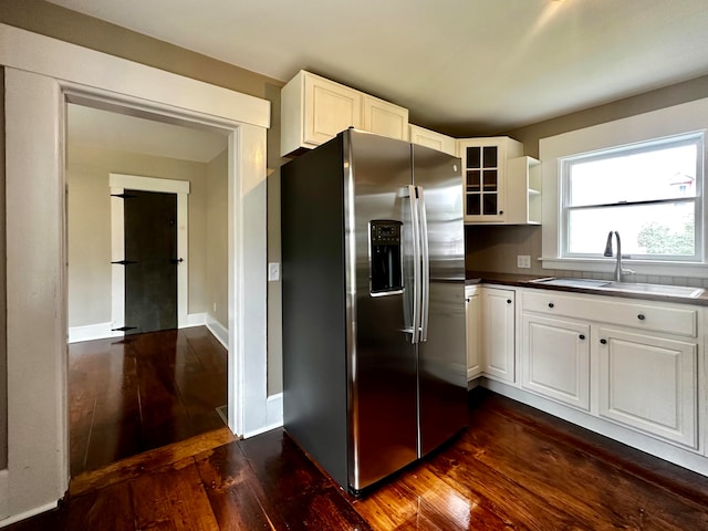 kitchen featuring glass insert cabinets, dark wood finished floors, white cabinets, stainless steel fridge, and a sink