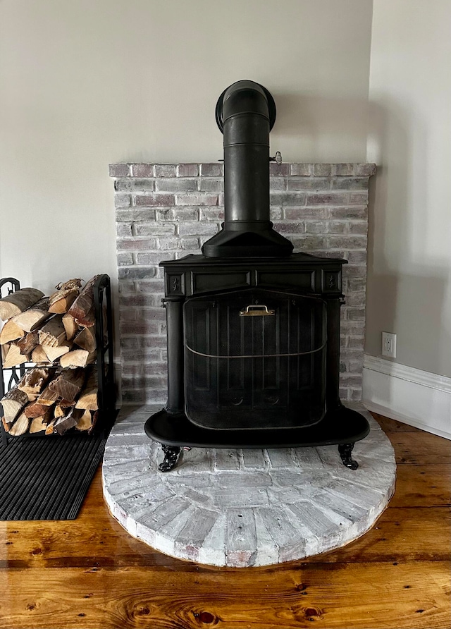 details featuring a wood stove, baseboards, and wood finished floors