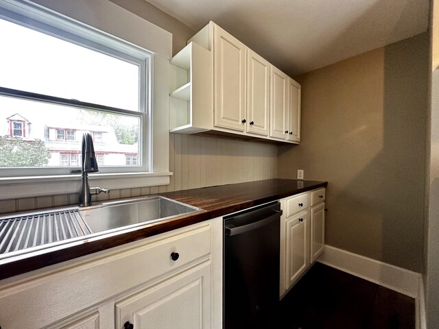 kitchen featuring dishwashing machine, white cabinetry, baseboards, and a sink