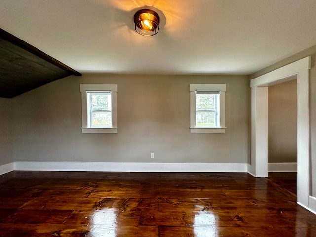 unfurnished room with a wealth of natural light, baseboards, dark wood finished floors, and vaulted ceiling