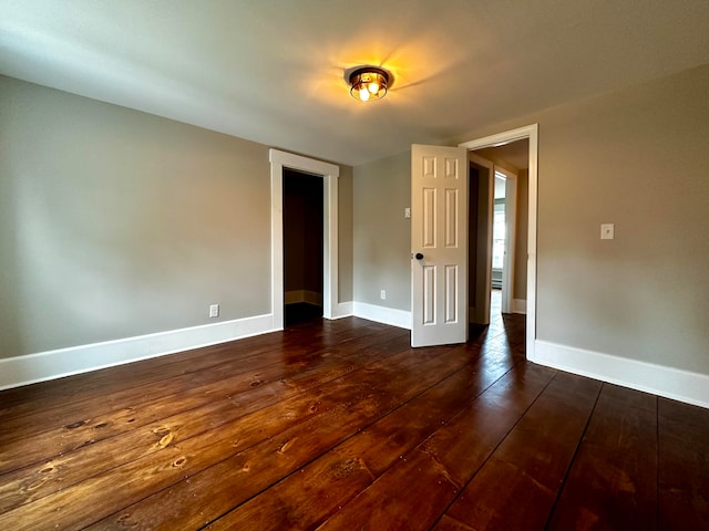 spare room featuring dark wood finished floors and baseboards