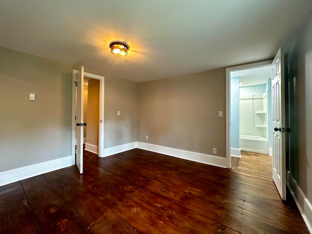 unfurnished room featuring baseboards and dark wood-style flooring