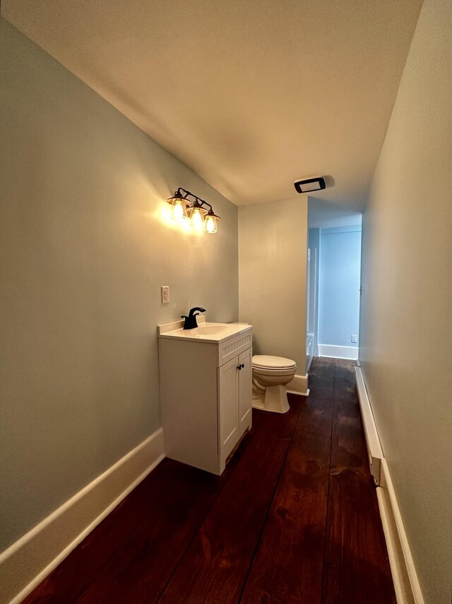 bathroom with toilet, vanity, baseboards, and wood finished floors