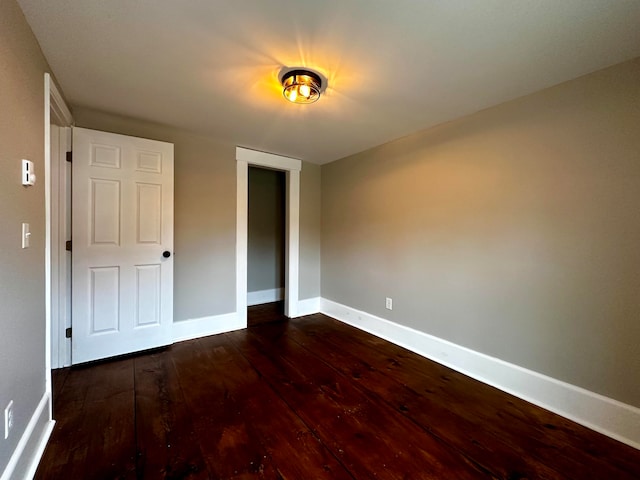 unfurnished bedroom featuring a closet, baseboards, and dark wood finished floors