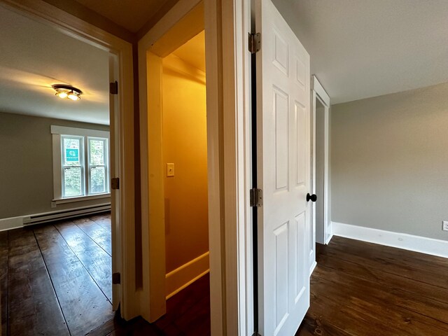 corridor featuring dark wood-type flooring and a baseboard heating unit