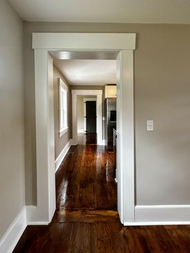 hall with baseboards and wood-type flooring