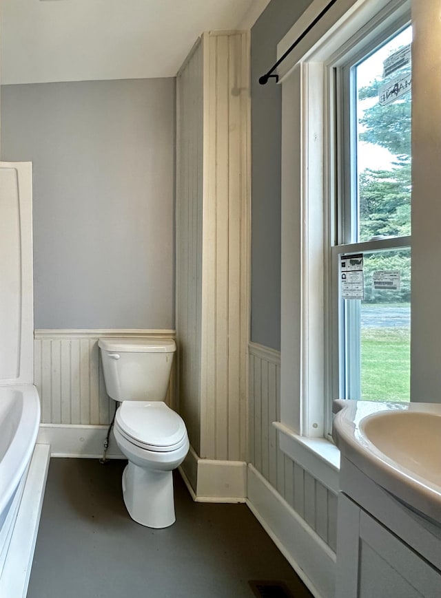 112 S St, Calais, ME 04619 - bathroom with a wainscoted wall, toilet, finished concrete floors, vanity, and a bathtub