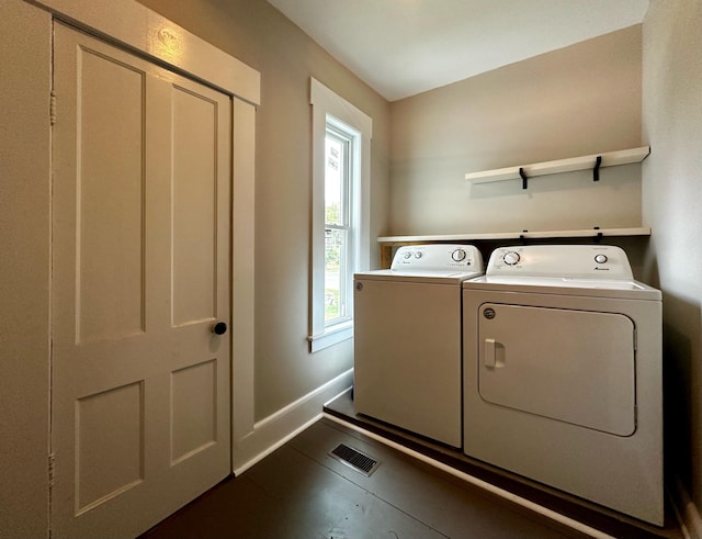 clothes washing area with dark tile patterned floors and washer and dryer