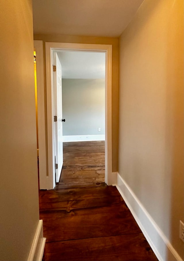 corridor with dark wood-type flooring and baseboards