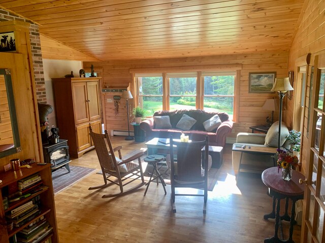 dining room featuring a wood stove, vaulted ceiling, light hardwood / wood-style floors, and baseboard heating